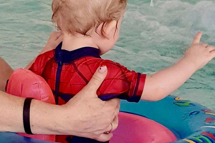 Täiskasvanu ujutab poissi ujumisrõngas